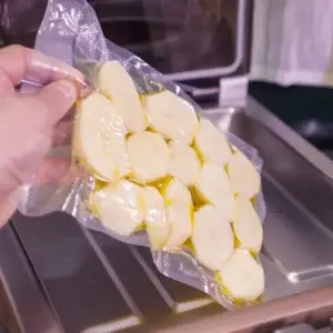 Auf dem Bild sieht man die Hand einer Person die einvakuumierte Kartoffeln aus einen Vakuumgerät nimmt.